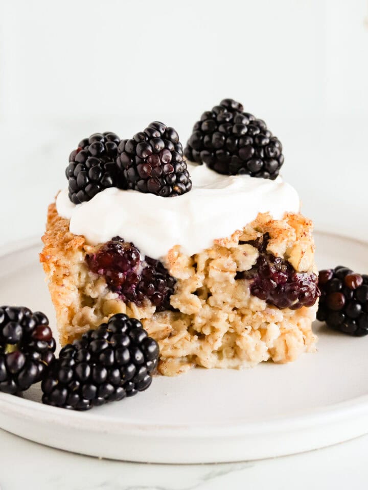 Square of baked oatmeal topped with vanilla yogurt and fresh blackberries.