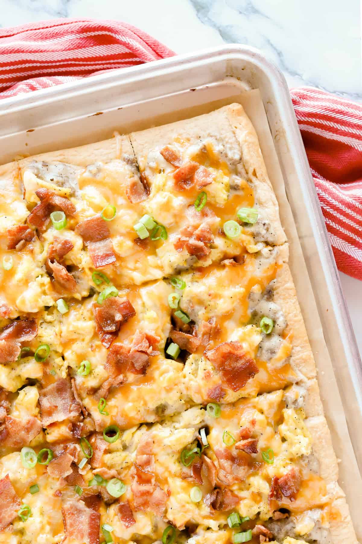 Sausage gravy breakfast pizza cut into squares on baking tray.