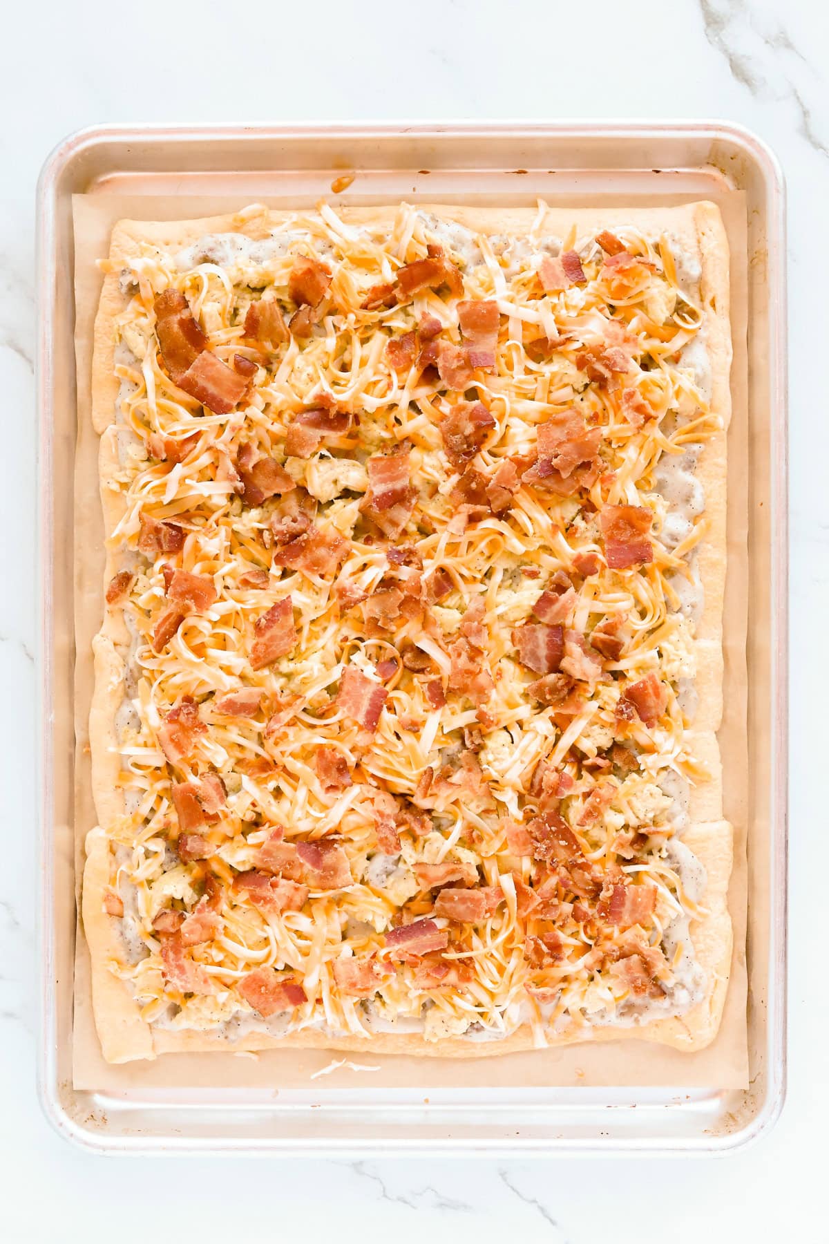Chopped bacon and shredded Colby jack cheese top of pizza.