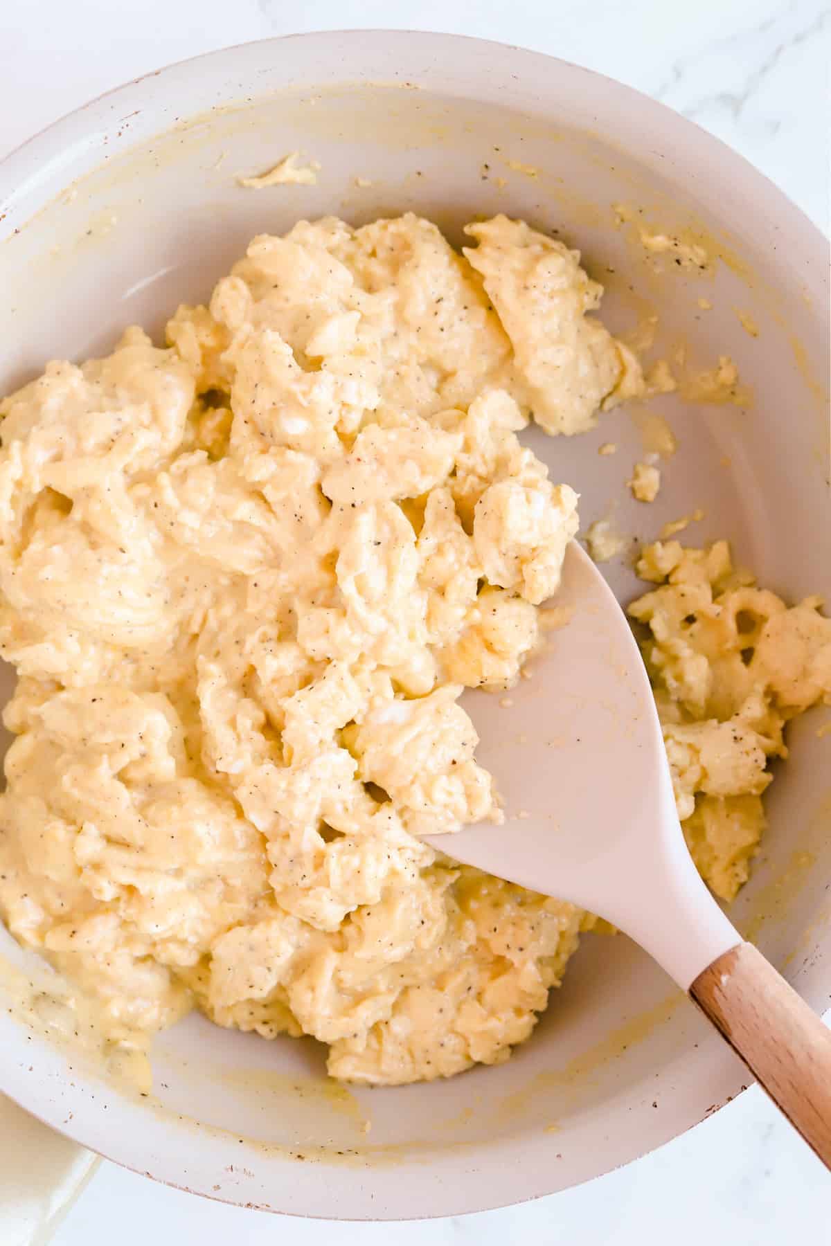 Fluffy scrambled eggs in a skillet with rubber spatula.