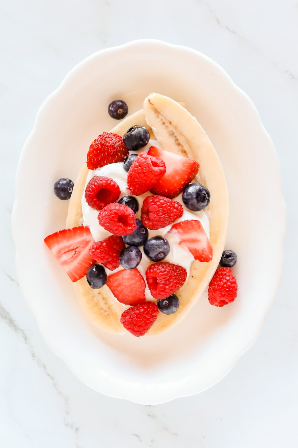Fresh strawberries, blueberries and raspberries over banana and yogurt.