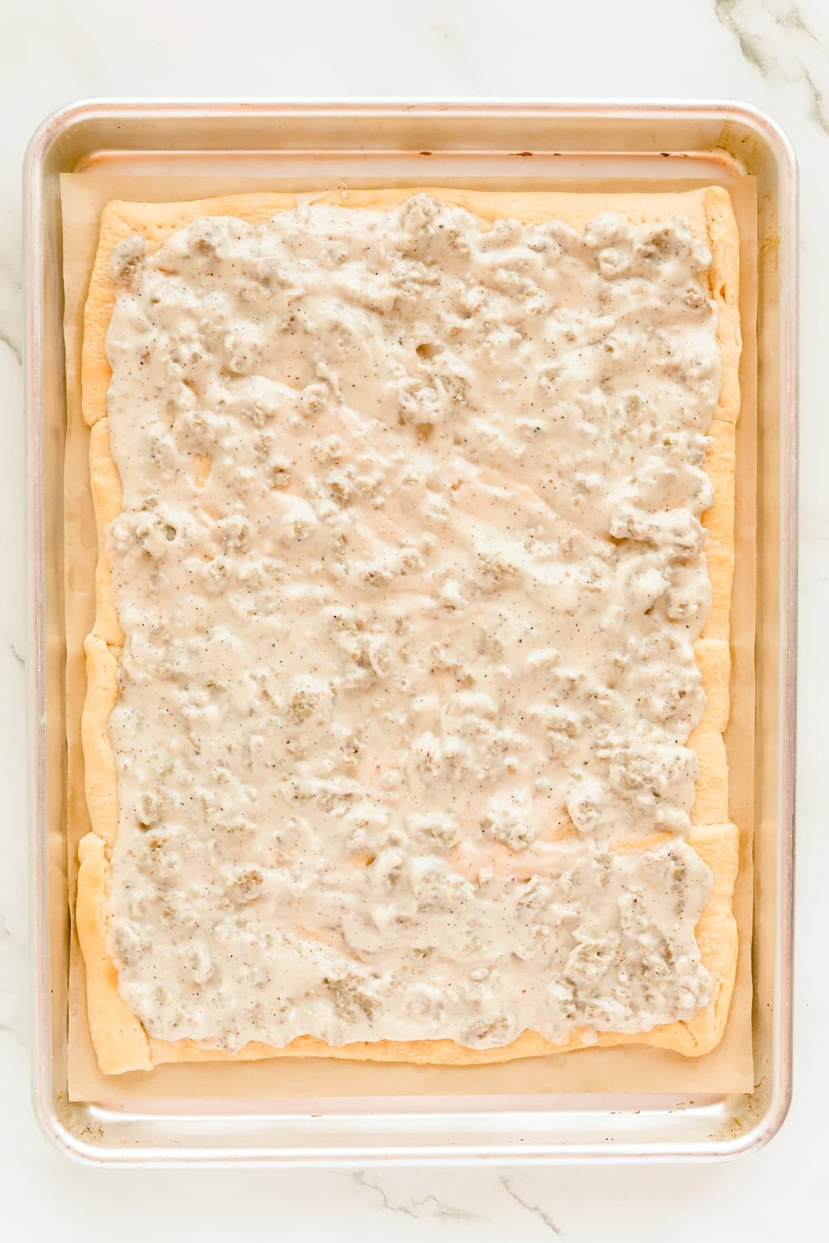 Sausage gravy spread over crescent roll crust.