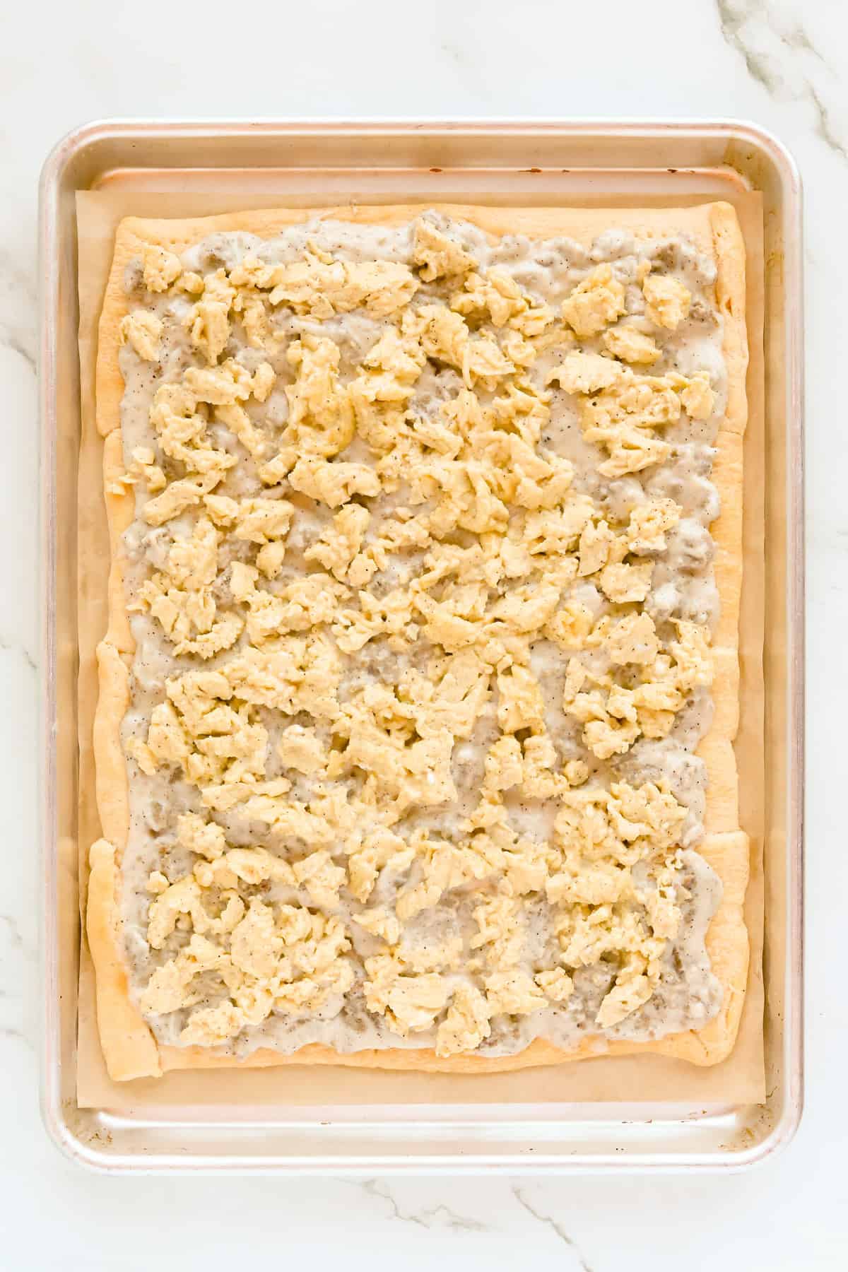 Scrambled eggs on top of sausage gravy and crust.