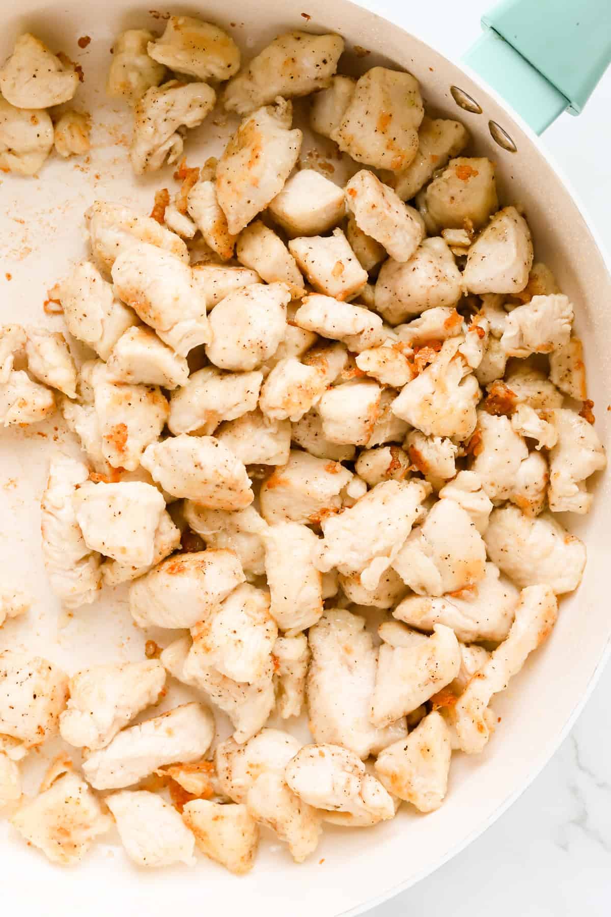 Browned chicken chunks in skillet.