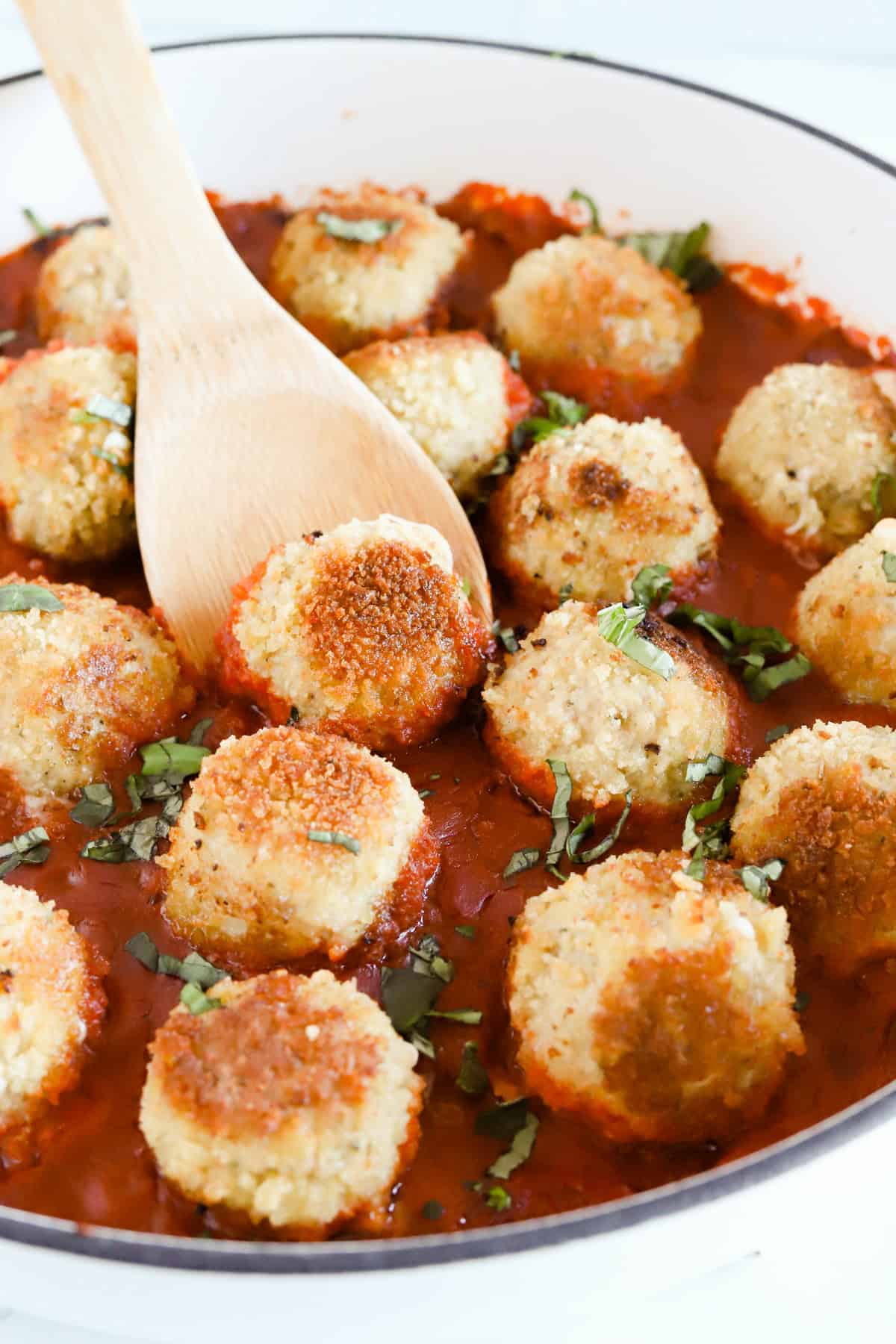 Chicken parm meatballs baked with marinara sauce in a ceramic skillet.