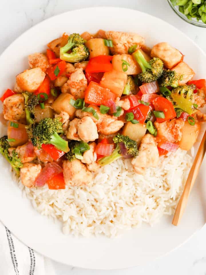 Featured image of pineapple chicken stir fry over rice on a white plate with chopsticks