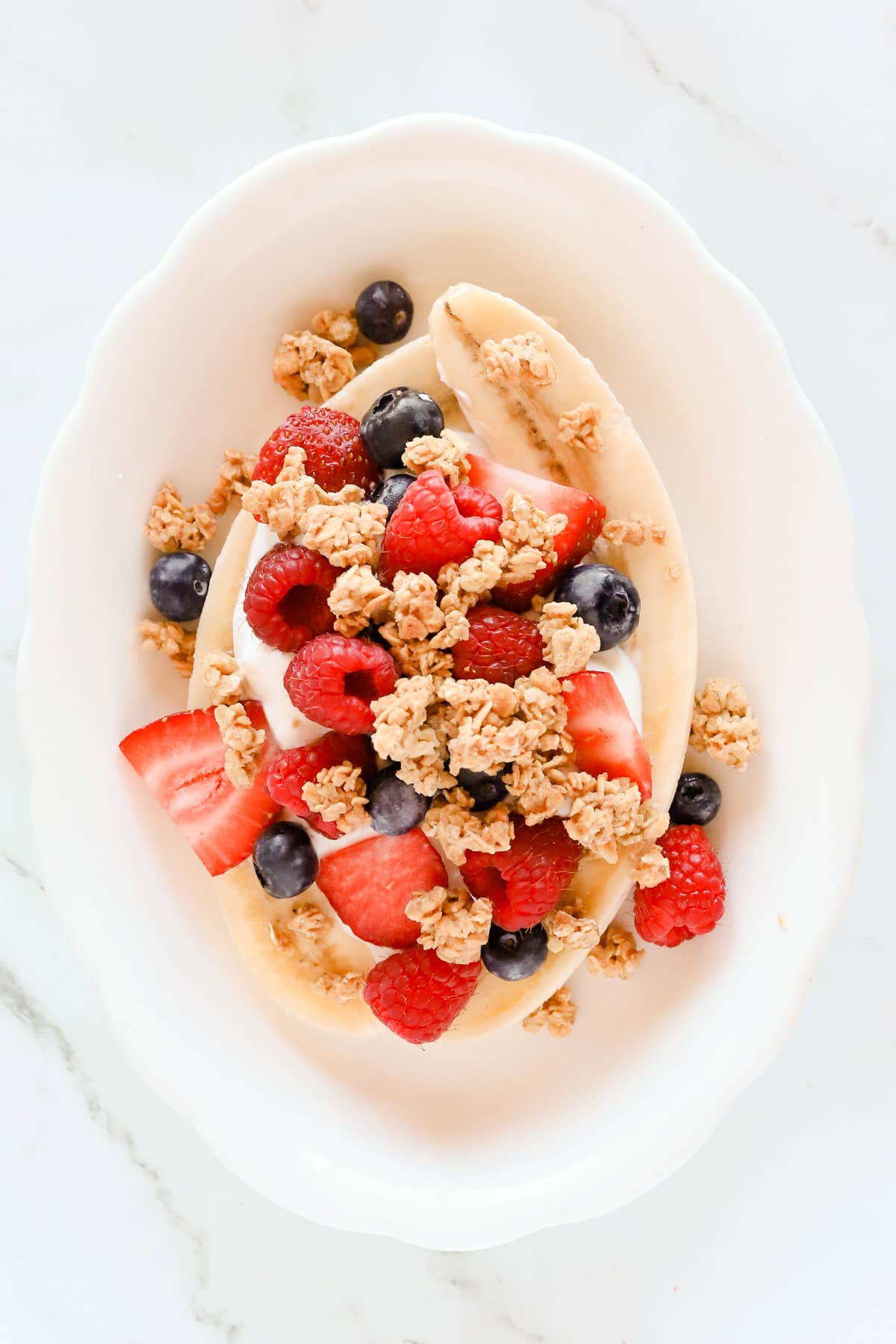Honey oat granola sprinkled over fresh berries, yogurt and banana.