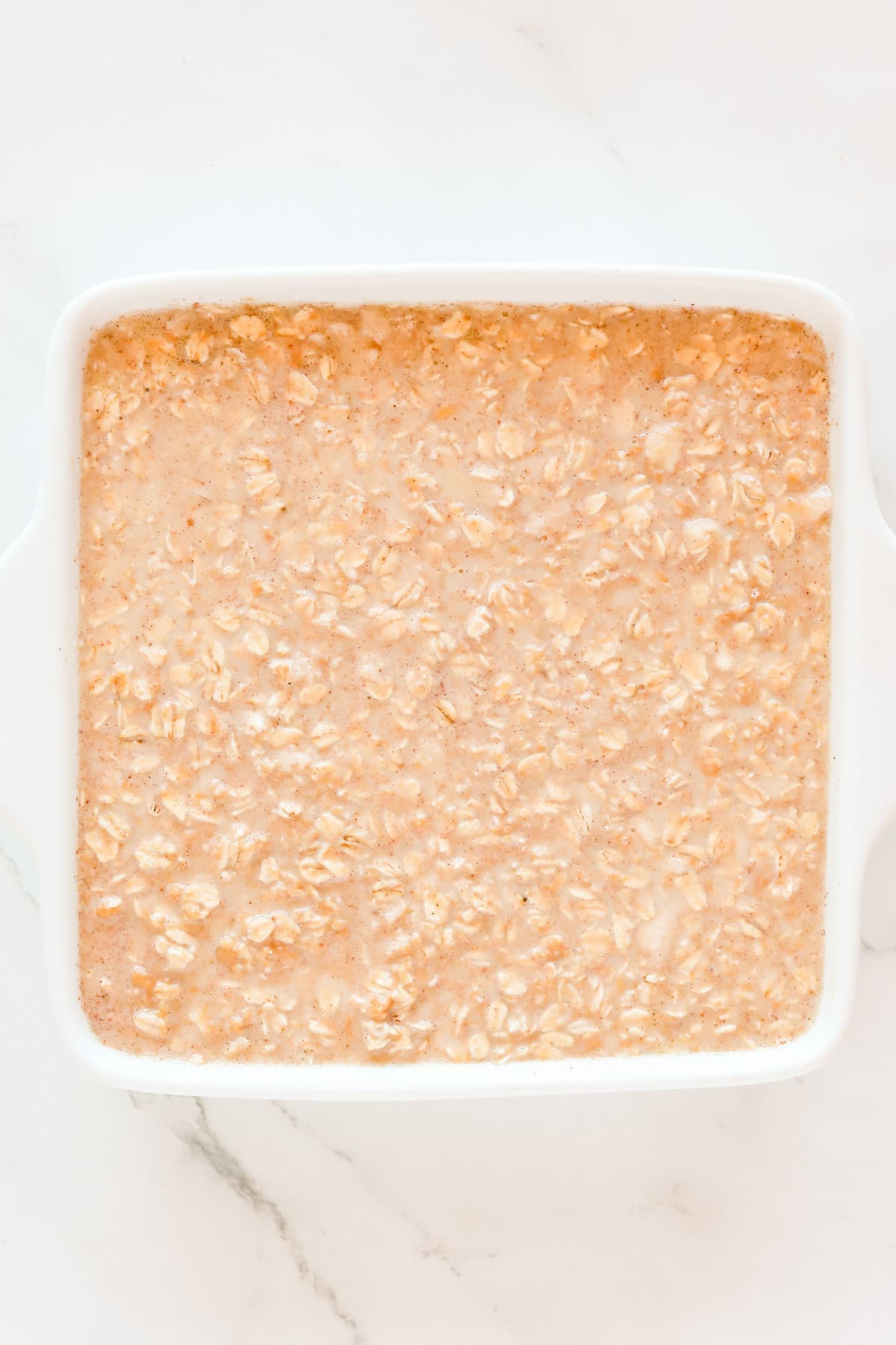Peanut butter oatmeal batter in a square white baking dish.