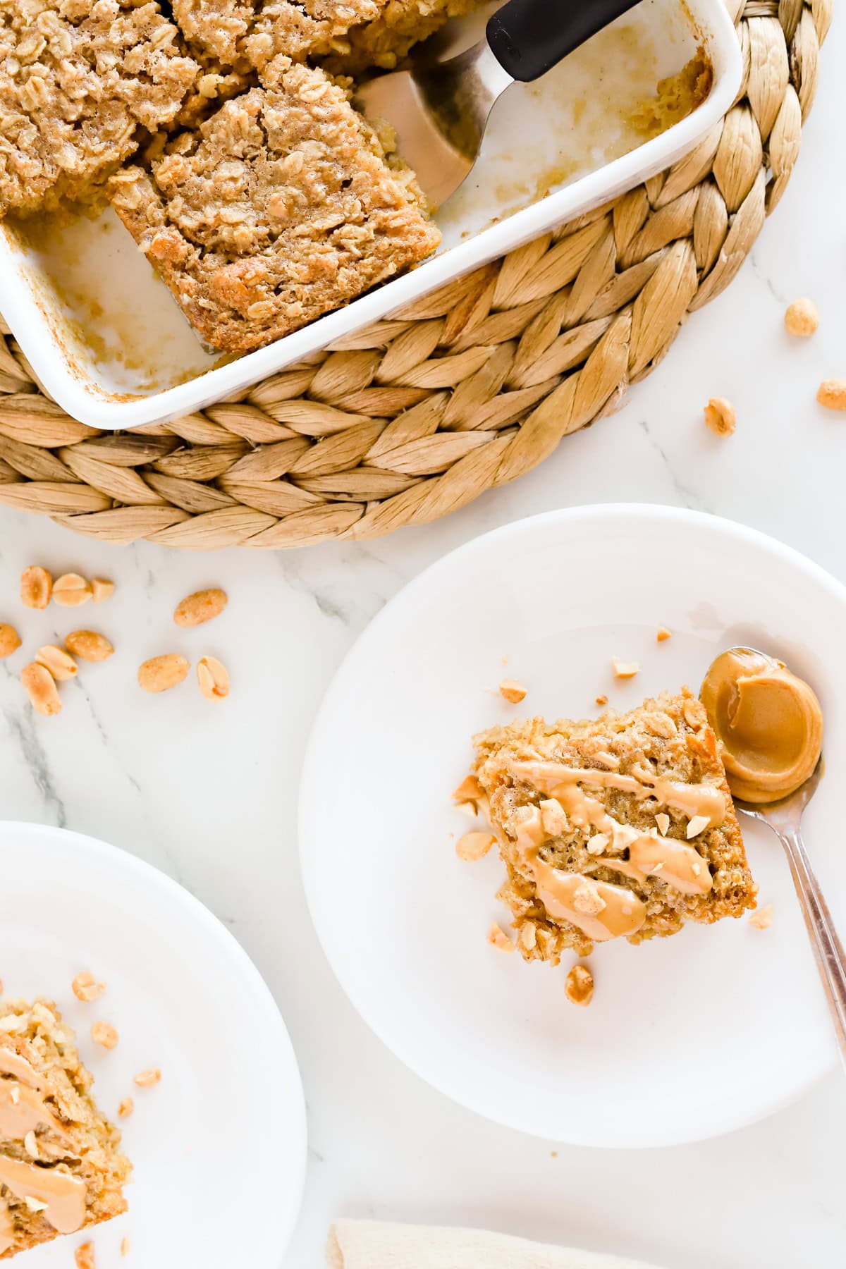 Overhead view of 2 plates of peanut butter oatmeal squares and white pan of oatmeal.