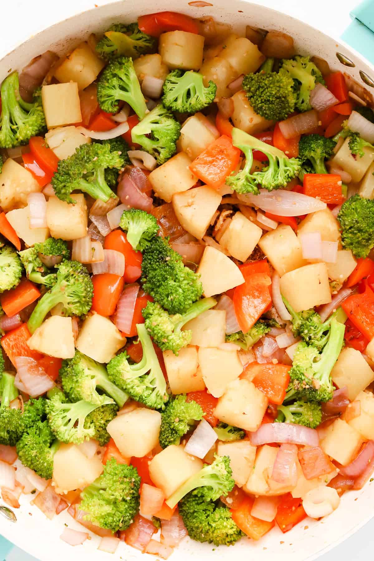 Sautéed vegetables and pineapple in a skillet.