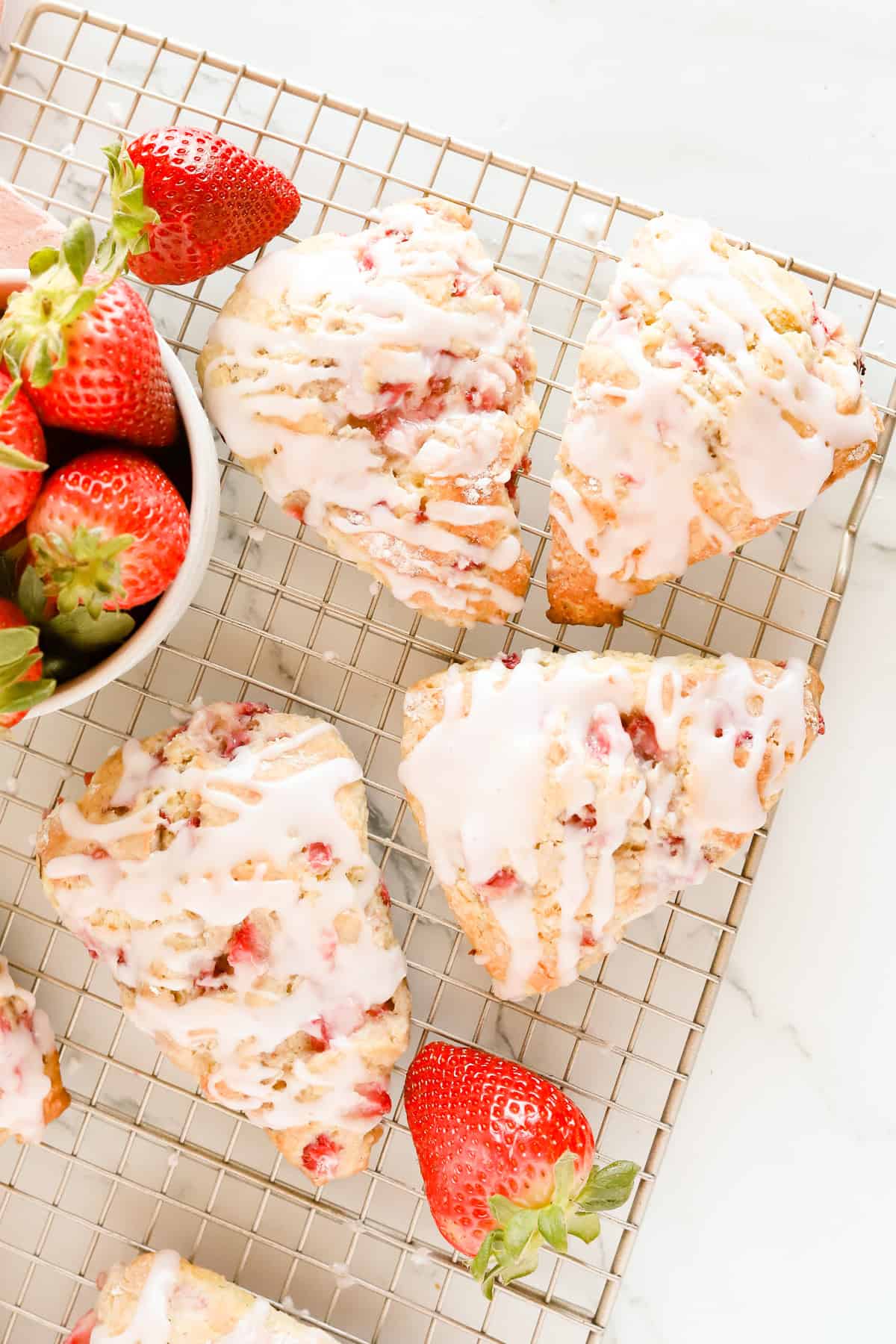 Strawberry scones on a wire rack with fresh strawberries.