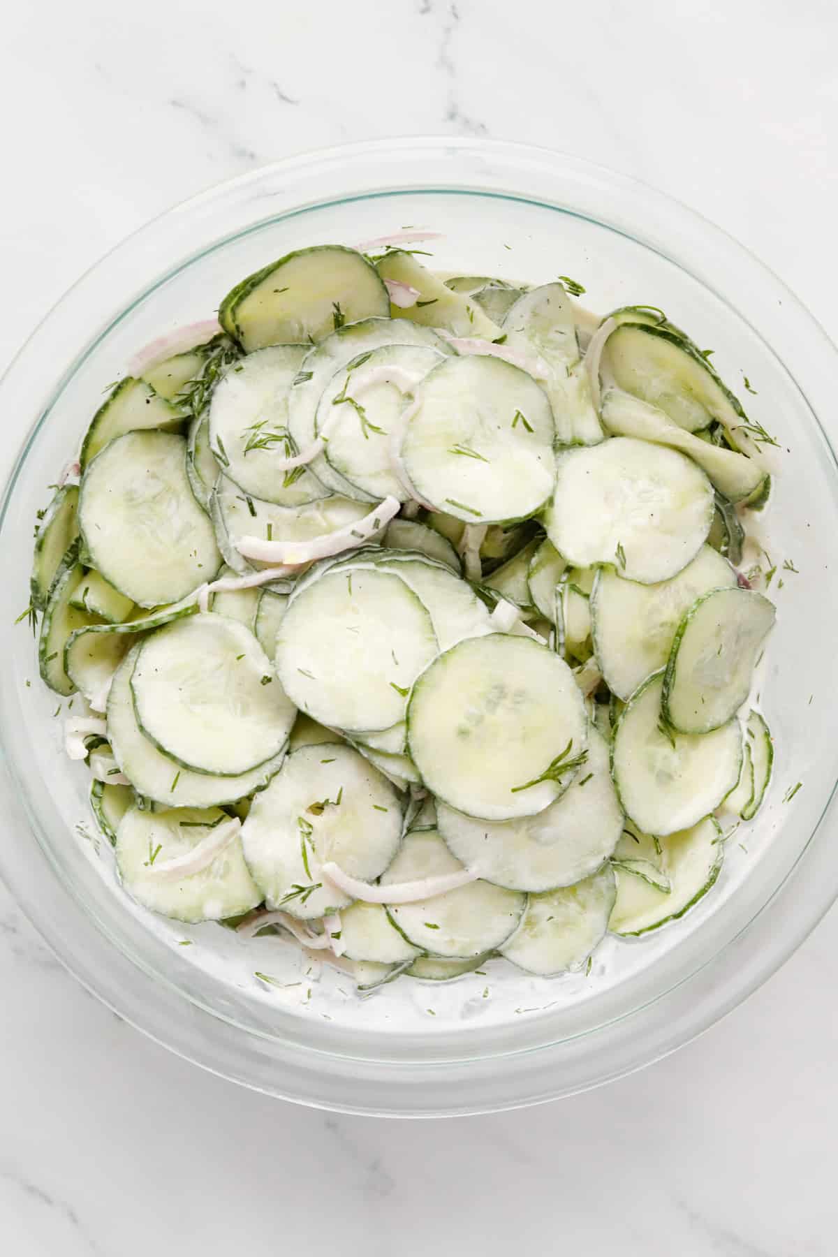 Mixed cucumber salad in a glass bowl.