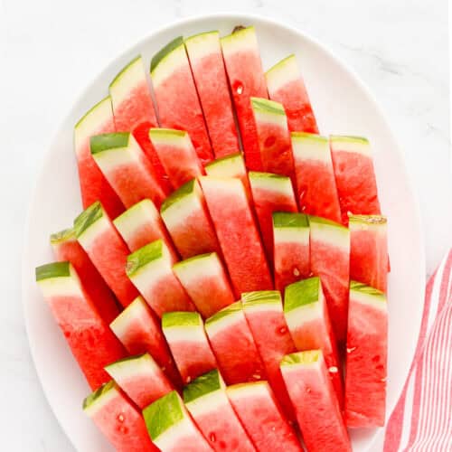 White oval platter of watermelon sticks.