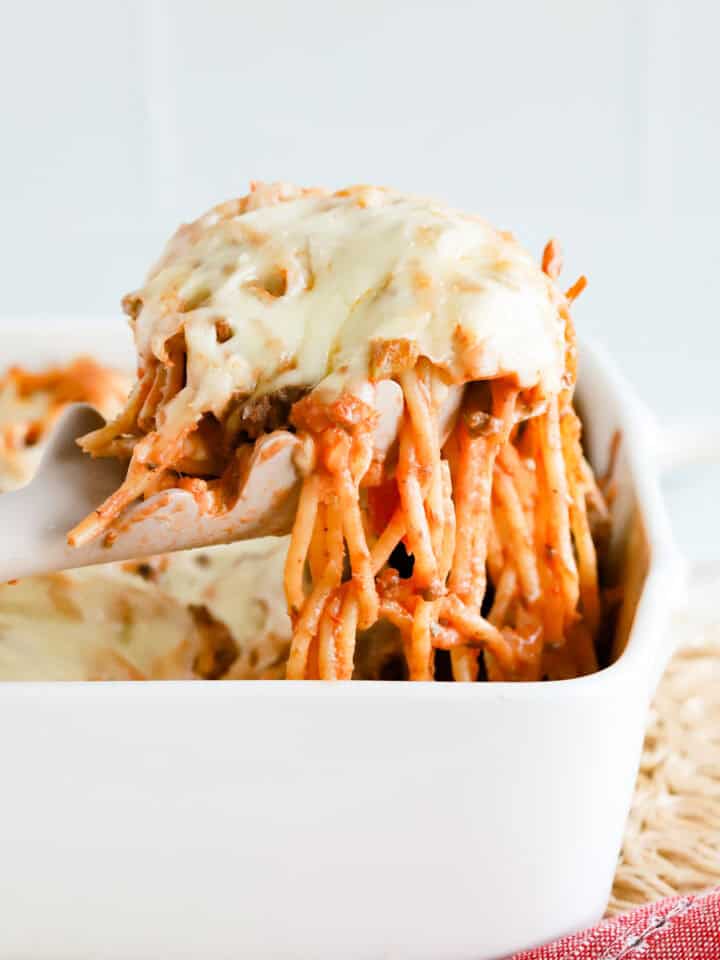 Featured image of a scoop of baked spaghetti casserole lifted out of white baking dish.