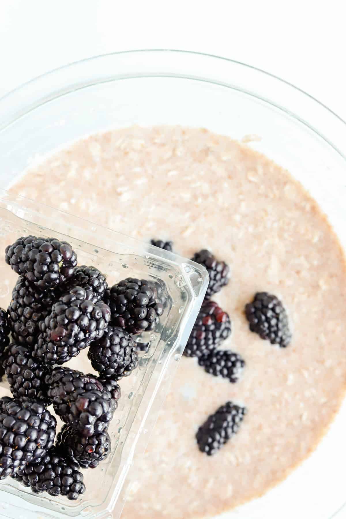 Clamshell of blackberries poured into oatmeal batter
