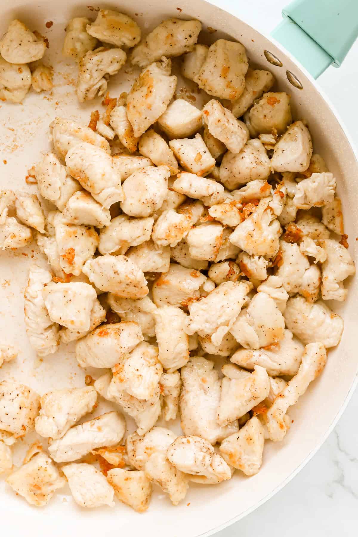 Browned chicken chunks in skillet.