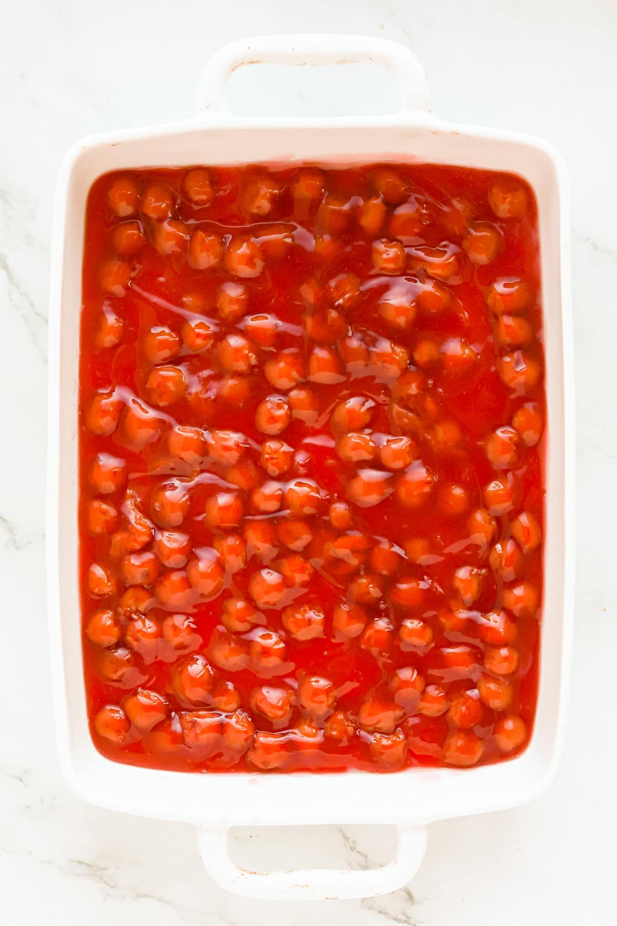 Canned pie filling spread in bottom of white 9x13 baking dish