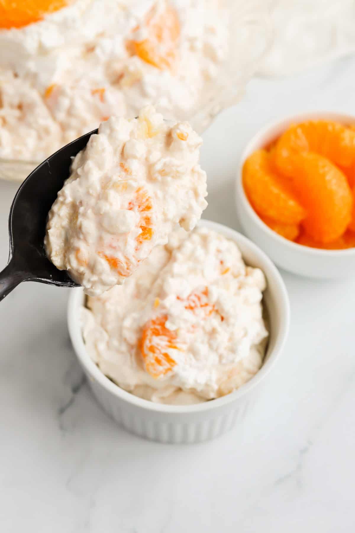 Black spoon scooping Salad into a white ramekin.