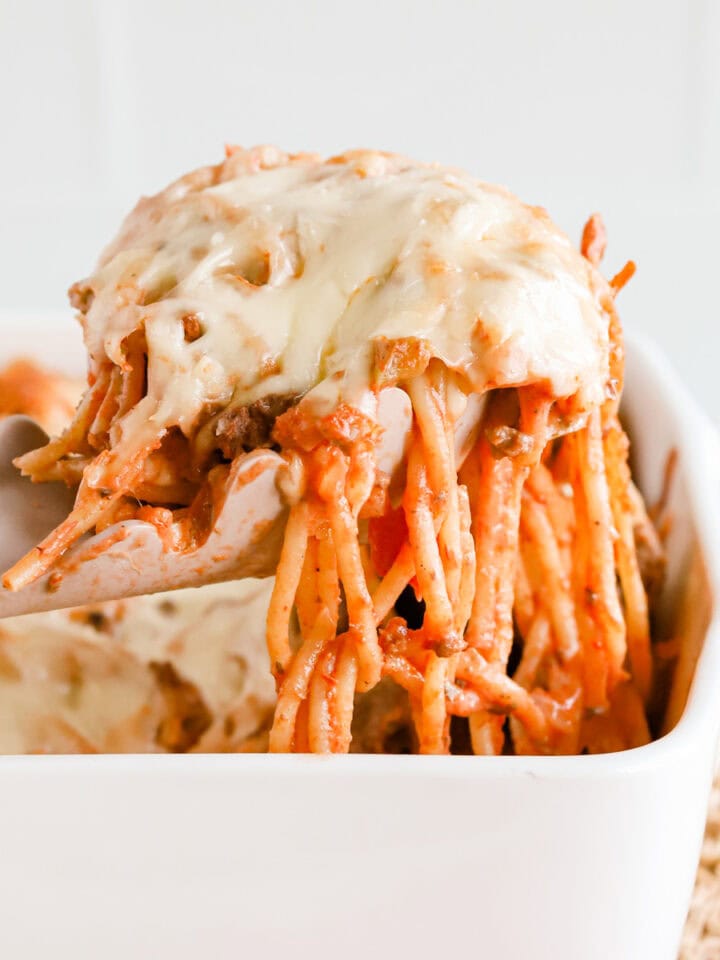 Featured image of a scoop of baked spaghetti casserole lifted out of white baking dish.