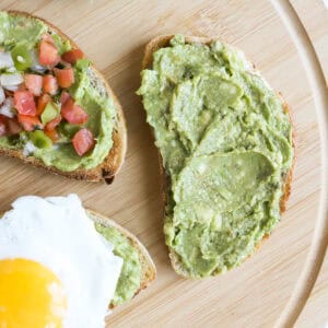 Featured image of guacamole on sourdough toast. One plain, one topped with a sunny side egg and one with pico de Gallo on top.