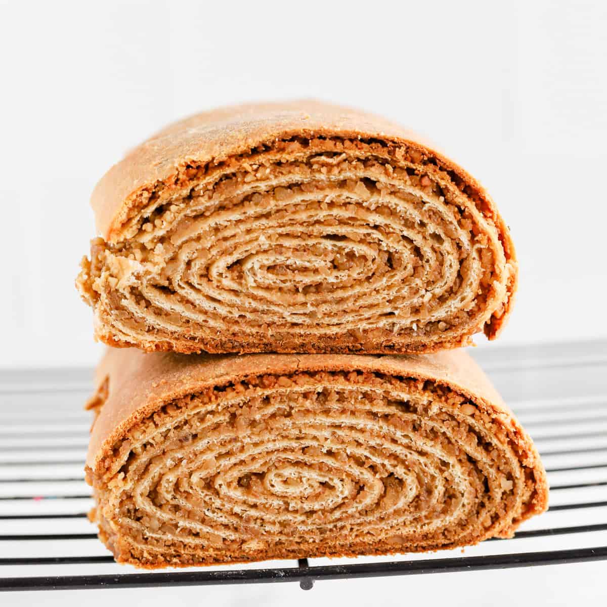 Potica loaves stacked on top of each other on wire rack revealing spiral center.