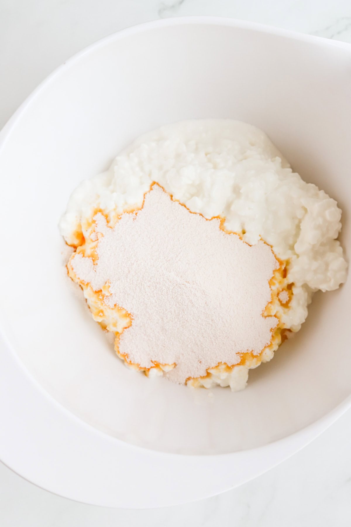 Powdered orange jello sprinkled on cottage cheese in a white bowl.