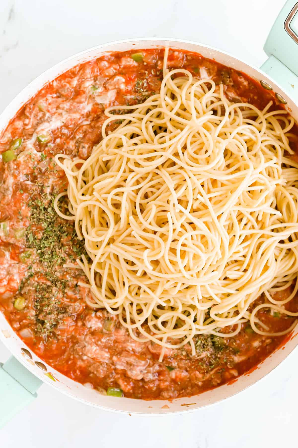 Noodles added to the meat sauce in the skillet.