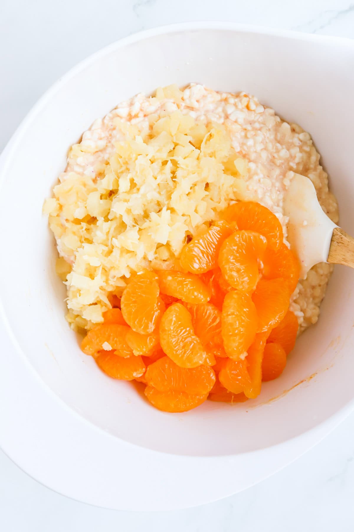 Crushed pineapple and mandarin oranges added to bowl of cottage cheese.