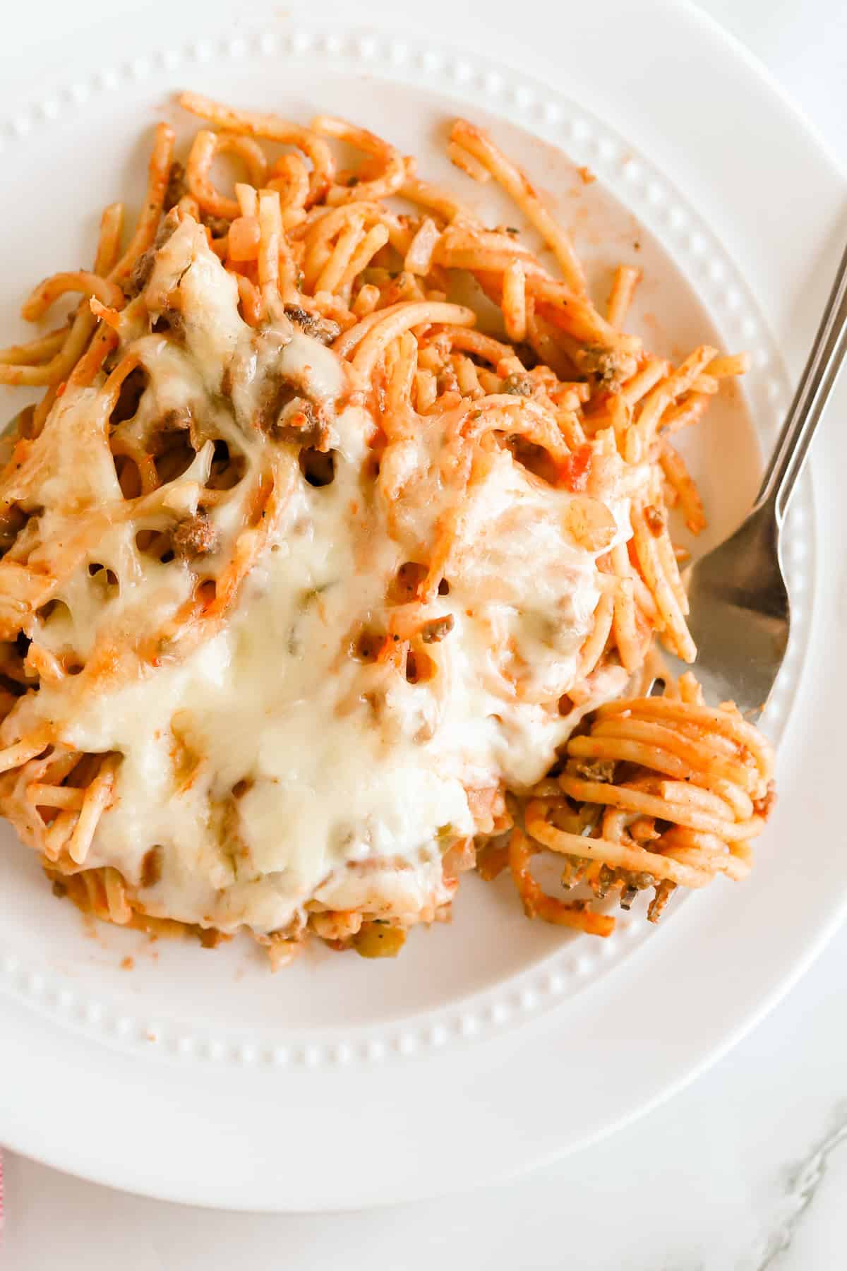 Spaghetti casserole on a white plate with a silver fork.
