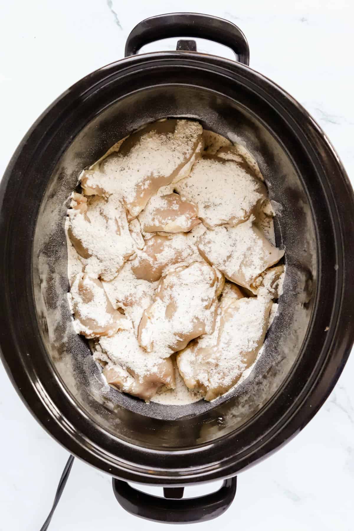 Chicken thighs in bottom of slow cooker sprinkled with ranch seasoning powder.