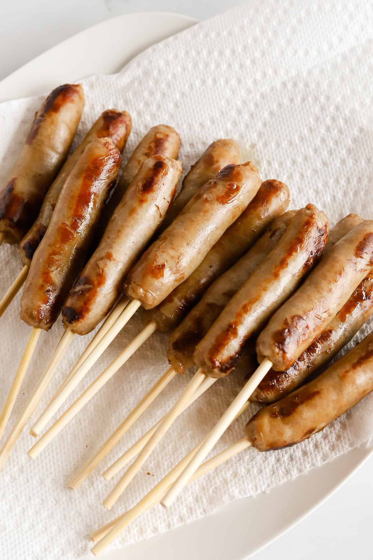Sausage links on wooden skewers on paper towel lined plate