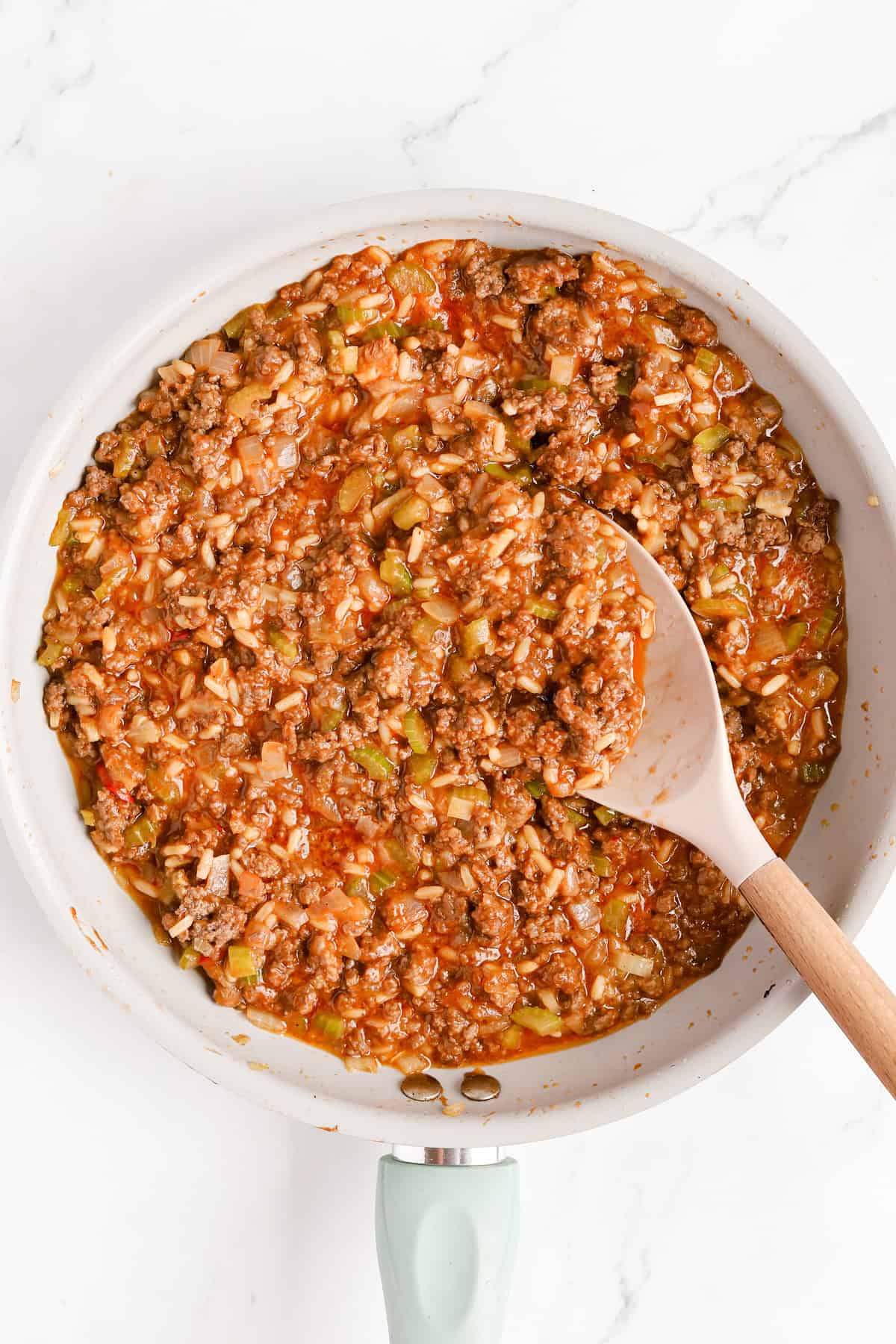 Sloppy Joe mixture in a skillet with a rubber spatula.