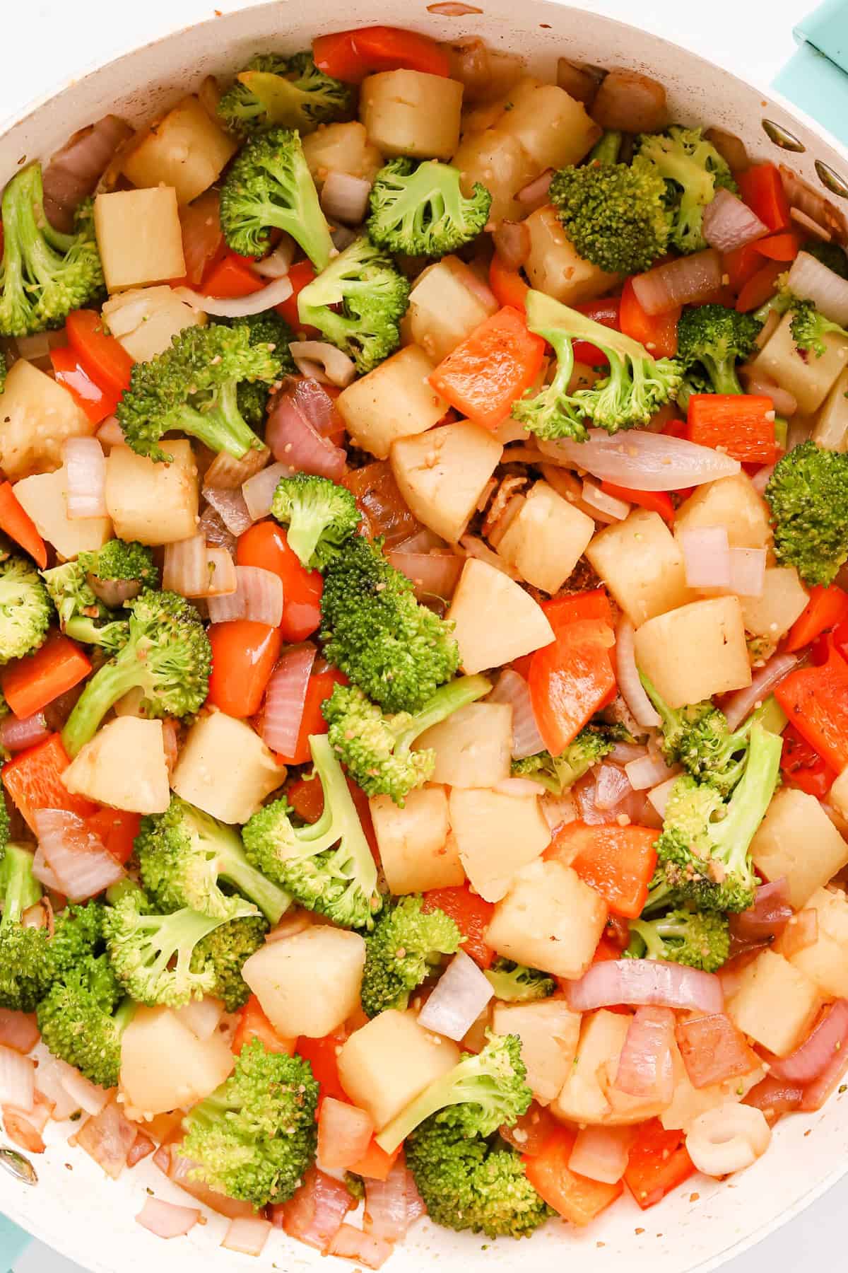 Sautéed vegetables and pineapple in a skillet.