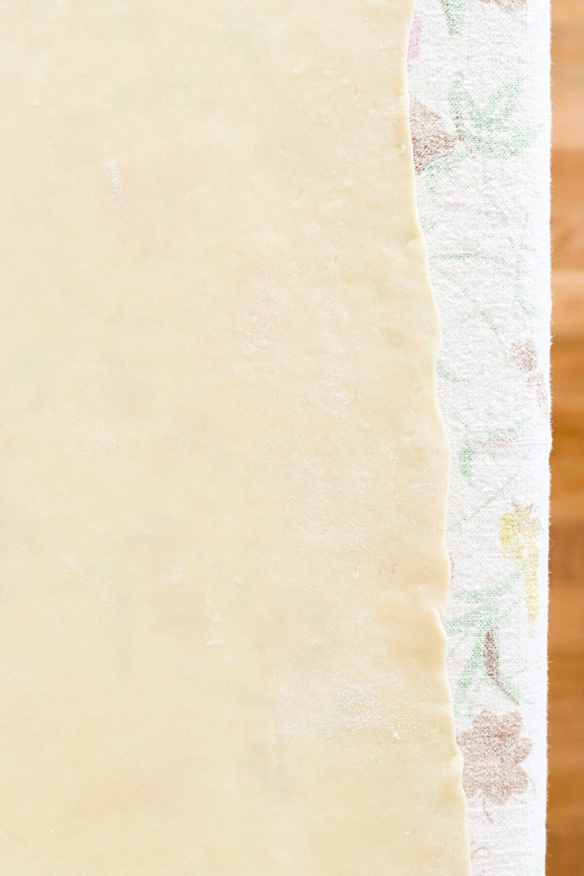 Thinly stretched dough on a flowered tablecloth.
