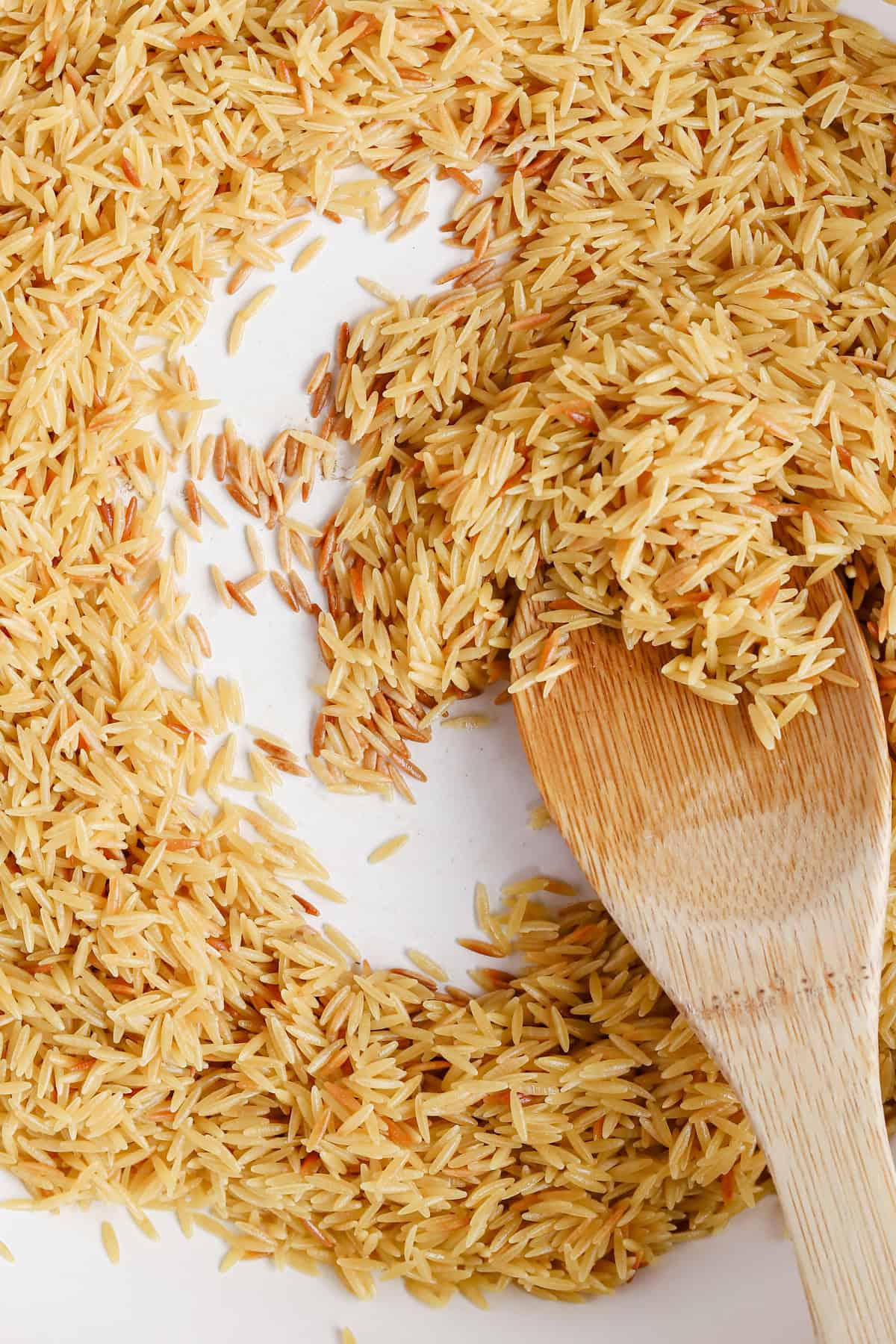 Toasted orzo in the bottom of a braiser pan.