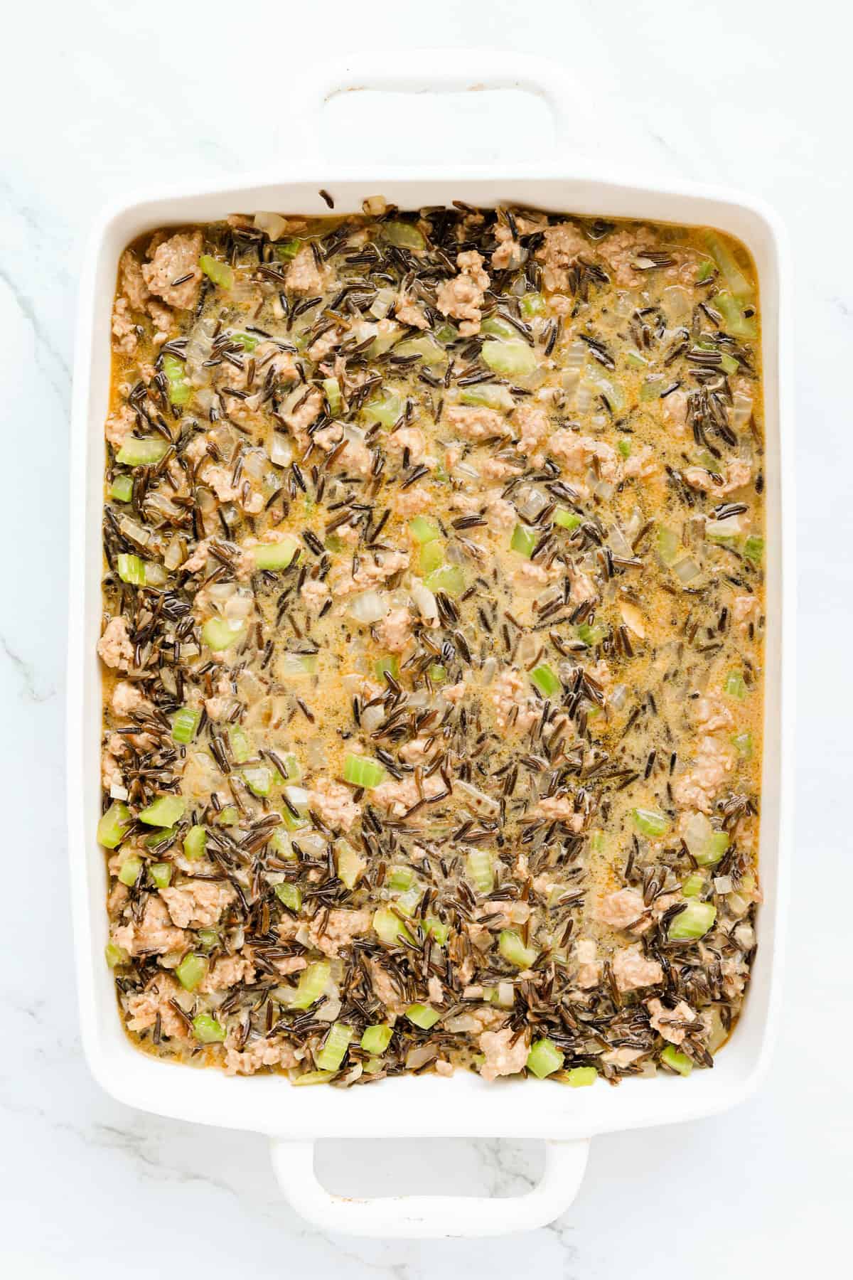 Uncooked casserole in a white baking dish.