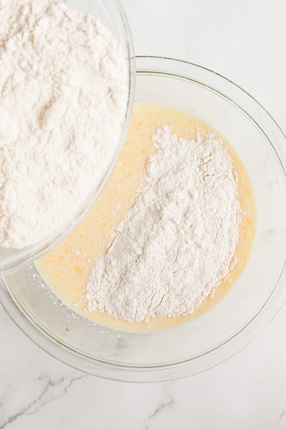 Dry ingredients added to wet ingredients in a glass bowl.