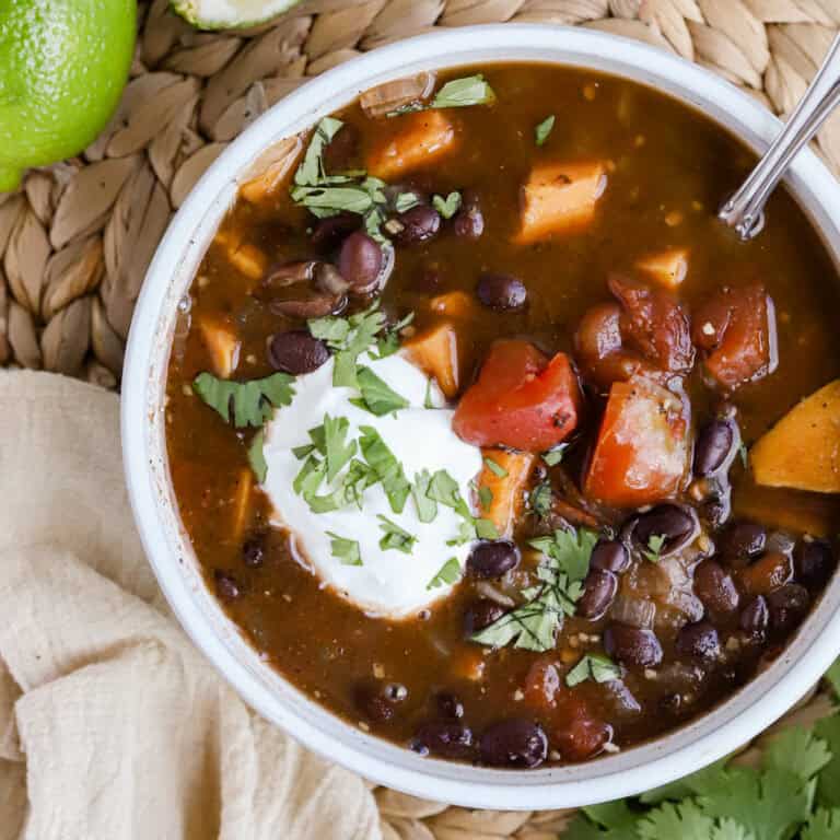 Square photo of bowl of soup garnished with sour cream and chopped cilantro.