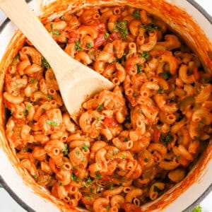 Featured image of chicken goulash in dutch oven stirred with wooden spoon.