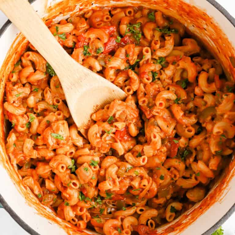 Featured image of chicken goulash in dutch oven stirred with wooden spoon.