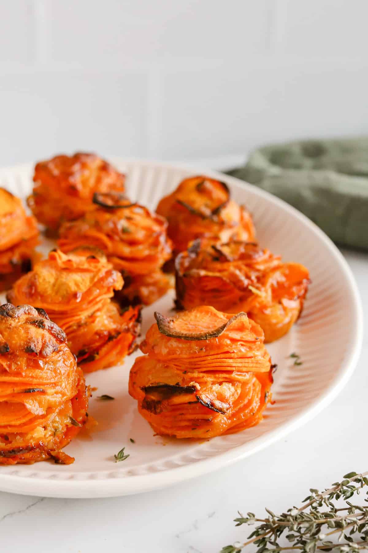 Sweet potato stacks displayed nicely on a white oval platter and garnished with thyme.