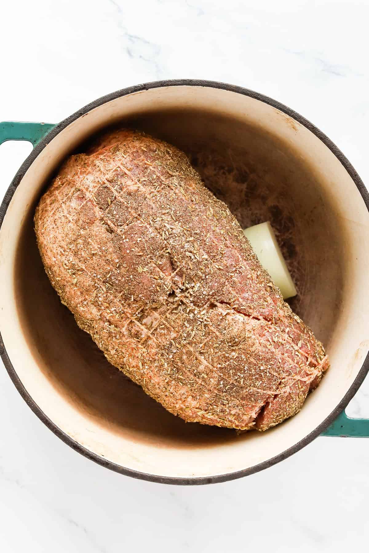 Seasoned pork butt in dutch oven on top of onion.