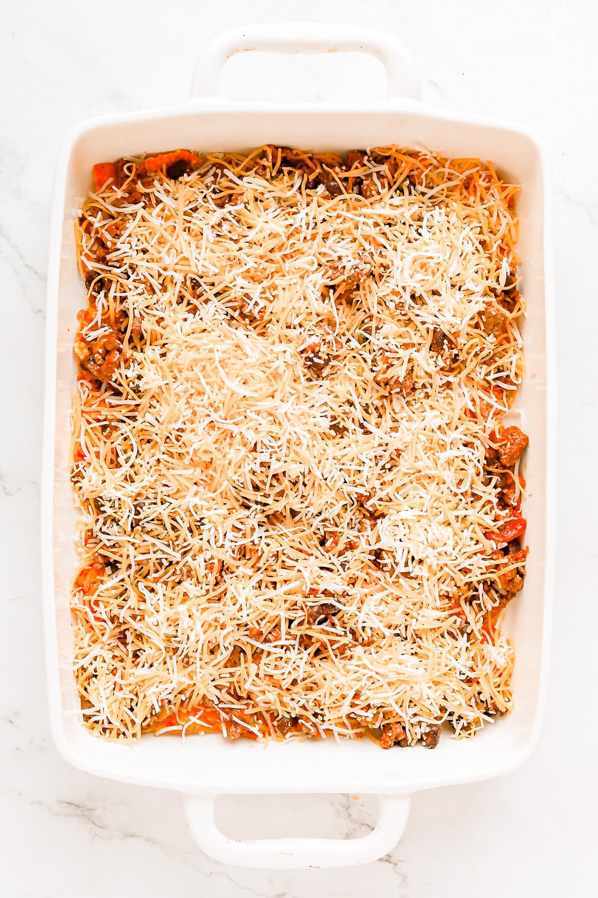 First layer of shredded Colby jack cheese on casserole.