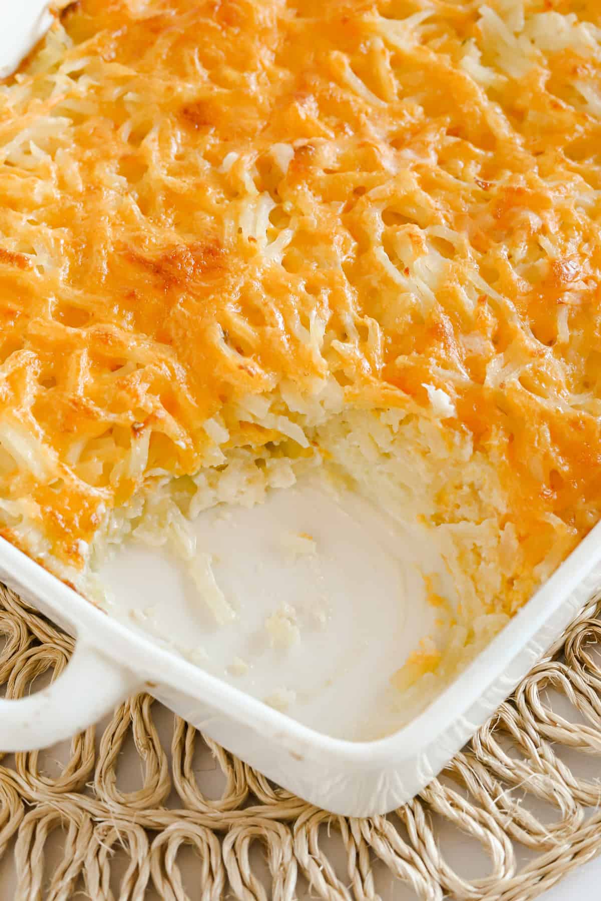 Baking dish of cheesy hashbrowns with a corner taken out so you can see the inside.