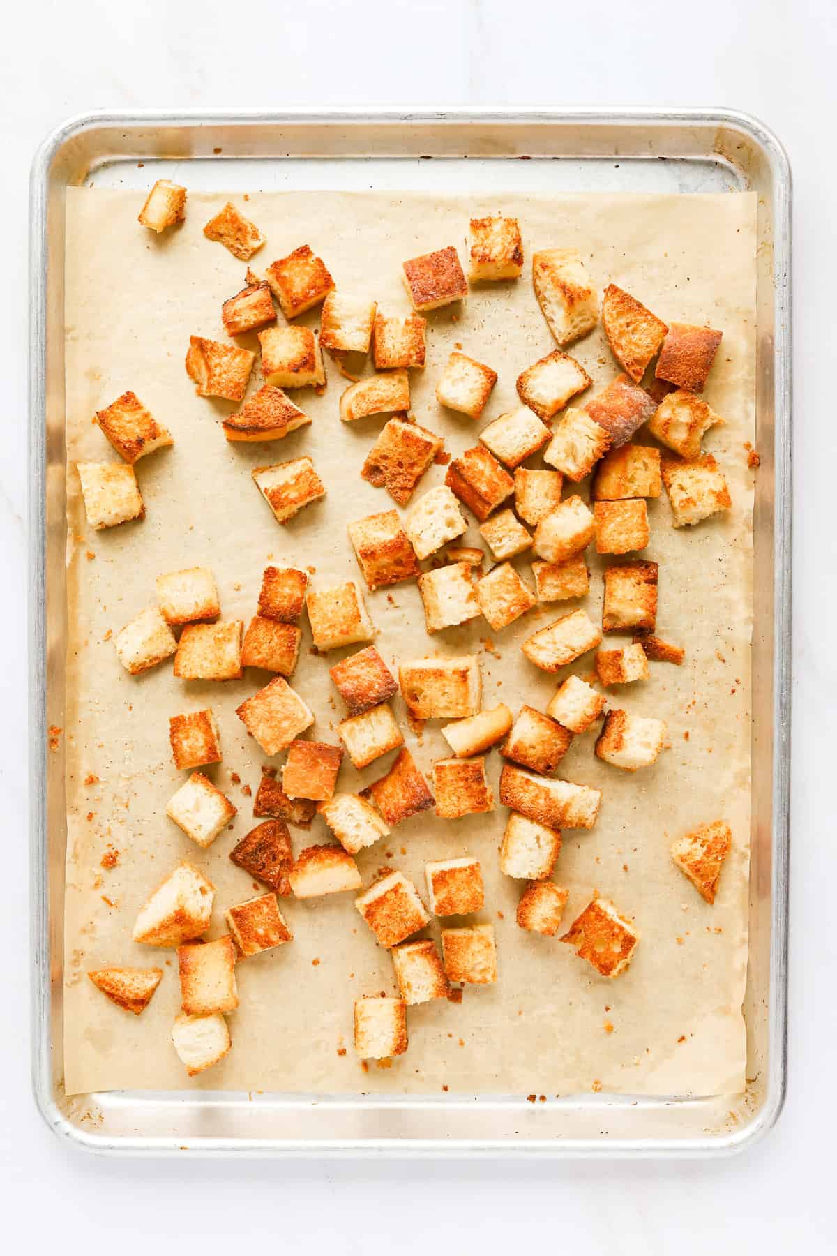 Crispy baked garlic croutons on a parchment lined sheet pan.