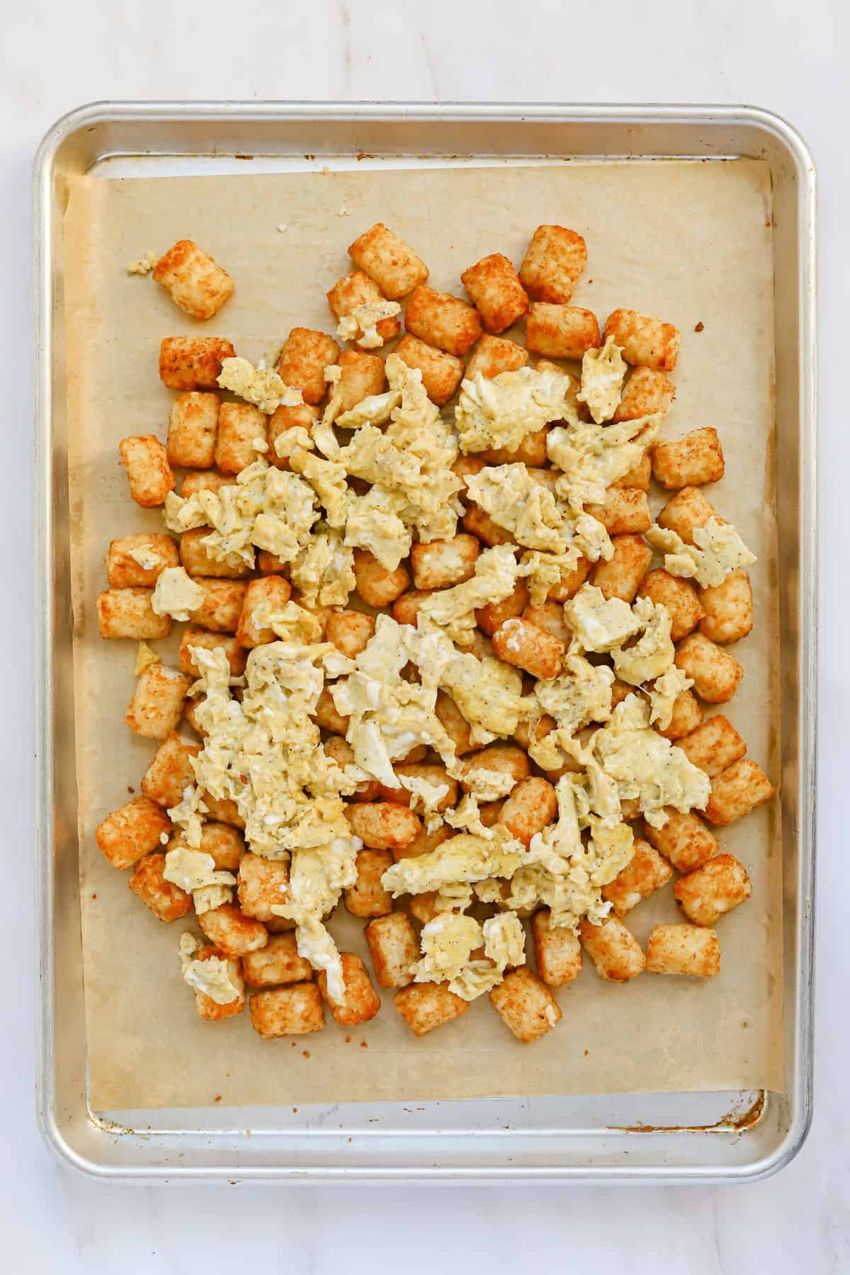 Scrambled eggs spread evenly over cooked tater tots.
