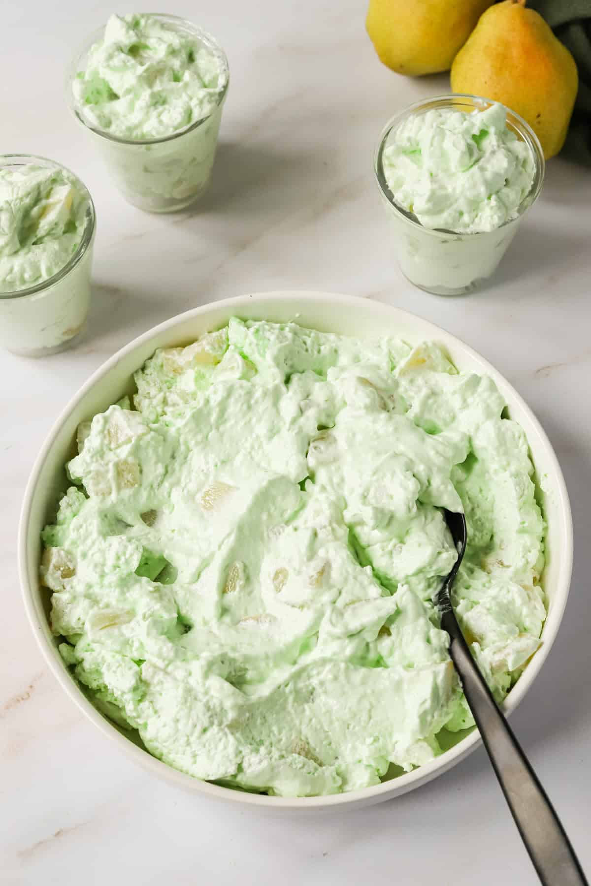 Seafoam salad in a white serving bowl with smaller servings in glass jars.