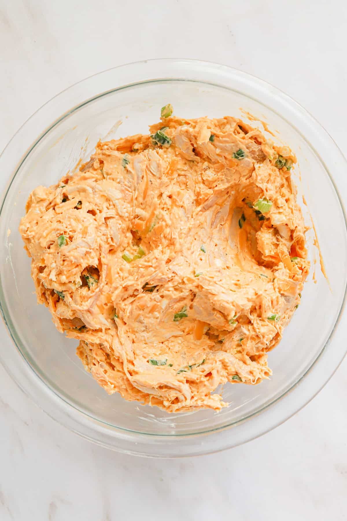 Mixed buffalo chicken filling in a glass bowl.
