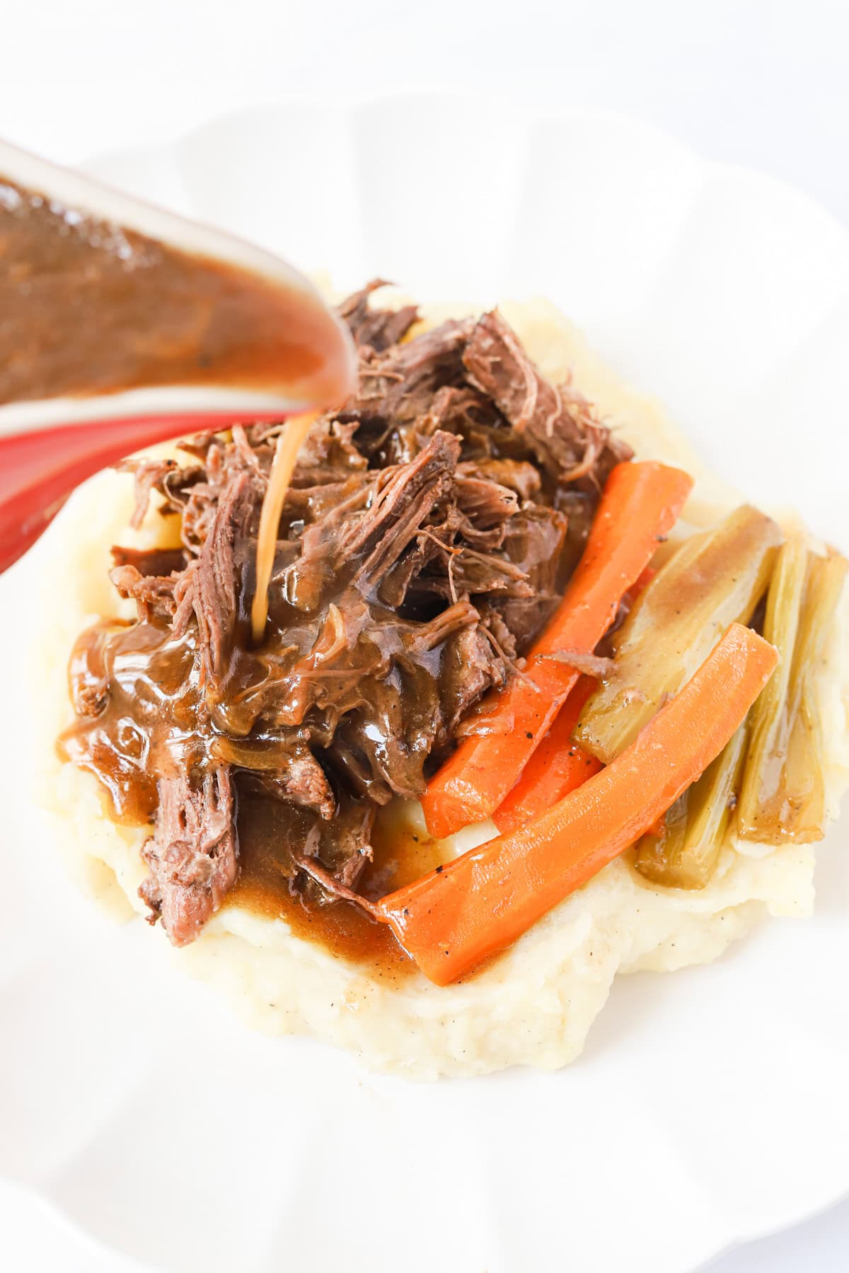 Gravy poured over shredded pot roast, potatoes and veggies.